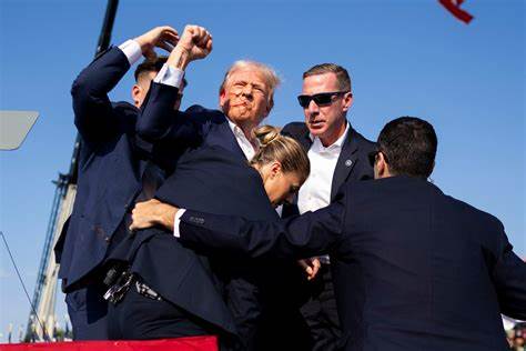 Trump is seen with blood on his face surrounded by Secret Service agents as he is taken off the stage at a campaign event at Butler Farm Show Inc. in Butler, Pennsylvania, on Saturday. (Rebecca Droke/AFP via Getty Images)